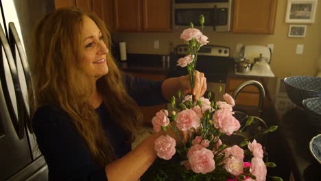 A-senior-red-haired-woman-puts-a-pink-flower-in-a-bouquet