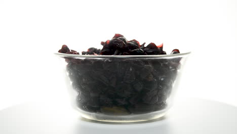 Rotating-glass-bowl-filled-with-dehydrated-cranberries-isolated-on-white-backdrop