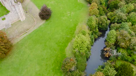 Aerial:-Framlingham-Castle-green-lawn-with-small-pond-beside-residence-area-at-Suffolk,-England---drone-shot