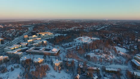 An-aerial-drone-shot-that-slowly-rises-upwards-while-panning-toward-the-left-to-reveal-views-of-a-densely-populated-urban-city-covered-in-sparkling-white-snow-during-winter