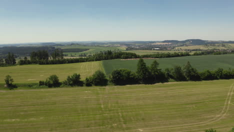 Rising-up-revealing-gentle-sloped-agricultural-fields-and-mountain-foothills-in-the-Czech-Republic,-aerial