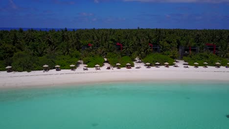 Aerial-pan-over-beach-parasol-resort-island-in-Maldives-on-picturesque-day