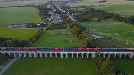 Luftaufnahme-Eines-Zugviadukts-Mit-Einem-Vorbeifahrenden-Zug-Und-Der-Umliegenden-Landschaft-Im-Hintergrund