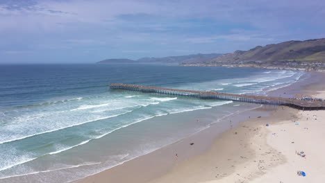 The-pier-at-Pismo-Beach,-ocean,-landscape-and-beach-on-a-beautiful,-sunny-day---aerial-parallax-view
