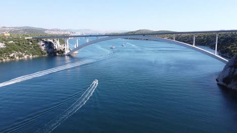 Sibenik-Bridge-at-Krka-River,-Dalmatia,-Croatia---Aerial-Drone-View-of-Sailing-Boats,-Arch-Bridge-and-Driving-Cars