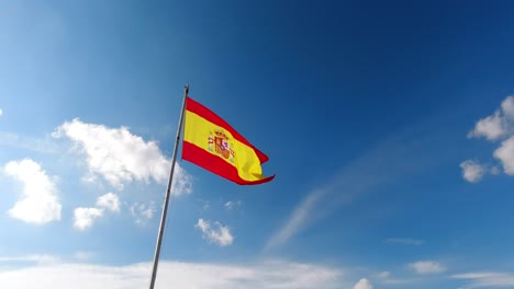 Handheld-ansicht-Der-Bunten-Spanischen-Flagge,-Die-Gegen-Blauen-Himmel-Weht