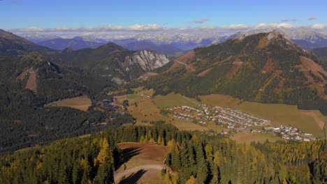 Aerial-pan-from-top-of-mountain-with-alpine-village-and-mountains-in-distance