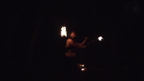 Asian-woman-spinning-poi-fireballs-in-circular-motion-during-night,-filmed-as-super-slow-motion-medium-shot