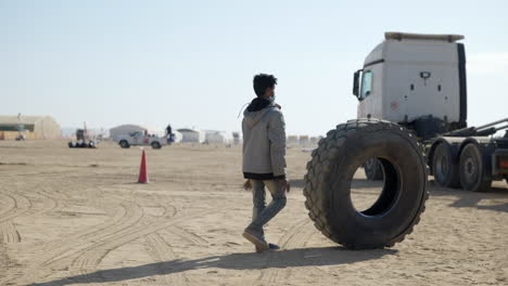 Lokaler-Arabischer-Mann,-Der-Reifen-Bei-Der-Dakar-rallye-Sammelt,-Von-Links-Nach-Rechts