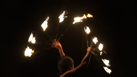 Mujer-Asiática-Girando-Ventiladores-De-Fuego-Brillantemente-Iluminados-Con-Fondo-Oscuro,-Filmada-En-Cámara-Lenta-Como-Cierre-Apretado