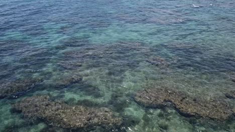 Drone-aerial-over-crystal-clear-blue-tropical-water-with-coral-reefs