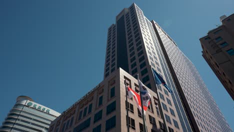 Sfc---Exterior-Del-Edificio-Del-Centro-Financiero-De-Seúl-Con-Banderas-Ondeando-En-Astas-De-Bandera-Contra-El-Cielo-Azul-Claro