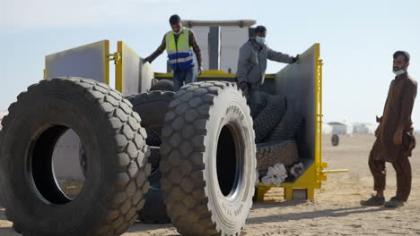 3-Arabic-men-at-the-Dakar-Rally-in-the-desert-with-large-tires-being-unloaded