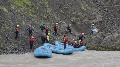 Grupo-De-Personas-Saliendo-De-Balsas-De-Goma-En-La-Costa-Rocosa-Del-Poderoso-Río-De-Montaña