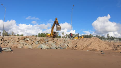 Bulldozer,-Der-Eine-Riesige-Mauer-Aus-Steinen-In-Der-Nähe-Eines-Strandes-Auf-Einer-Tropischen-Insel-Erstellt-Videohintergrund-|-Bulldozer-Maschine-Bei-Der-Arbeit-Für-Die-Entwicklung-Des-Strandes