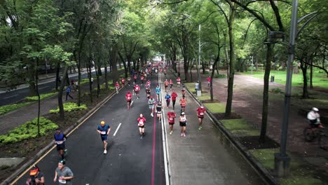 Toma-De-Un-Dron-Hacia-Atrás-De-Los-Corredores-De-La-Maratón-De-La-Ciudad-De-México-Mientras-Corren-Por-La-Avenida-Paseo-De-La-Reforma