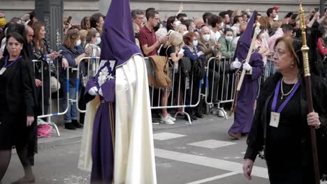 Nazareno-En-Túnica-Morada-Y-Capuchas-Y-Manolas-En-Vestidos-Negros-Con-Mantilla-Portando-Velas-Y-Marchando-Entre-Multitudes-Durante-El-Viernes-Santo,-Semana-Santa,-En-Calles-De-Madrid,-España