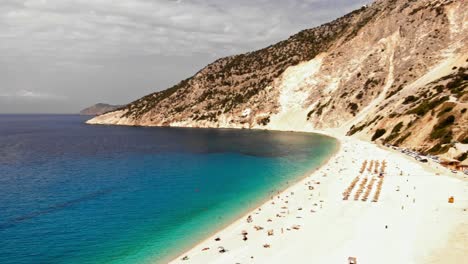 People-enjoying-the-white-sand-of-the-Myrtos-Beach-on-a-sunny-day--Wide-pan
