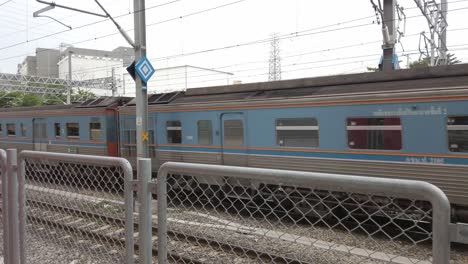 Thai-local-old-classic-train-or-tram-on-the-railway-with-utility-poles-tower-and-cable-wires-in-a-terminal-station-in-an-urban-city-in-public-transportation,-energy-electric-technology