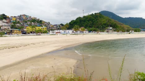 Angra-dos-Reis,-Rio-de-Janeiro,-Brazil---October-17,-2022-Praia-do-Anil-in-Angra-dos-Reis-with-car-and-pedestrians-on-Avenida-Ayrton-Senna-in-Angra-dos-Reis-in-the-background