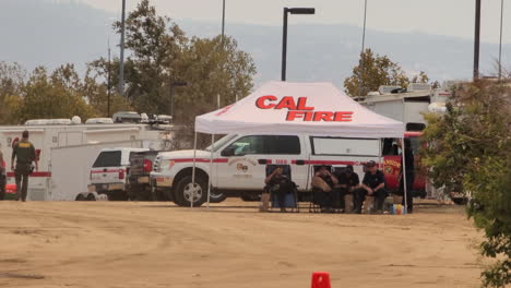 Schwenkschuss-Feuerwehr-Campingplatz-Mit-Feuerwehrleuten,-Die-Im-Schatten-Sitzen-Und-Sich-Ausruhen