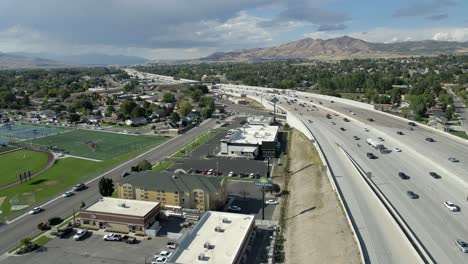 Tráfico-De-Carreteras-En-Lehi,-Utah-Con-Laderas-De-Silicio-Y-Las-Montañas-En-El-Fondo---Retroceso-Aéreo