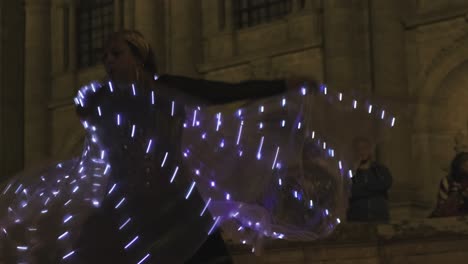 Mujer-Realiza-Un-Baile-Con-Alas-Led-En-El-Festival-Medieval-De-Lugo,-Movimiento-De-Brillo-Hipnótico