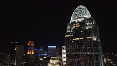 Aerial-view-away-from-the-illuminated-Great-American-Tower-at-Queen-City-Square,-revealing-the-night-skyline-of-Cincinnati,-Ohio,-USA