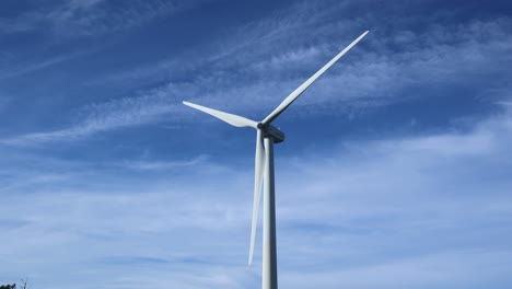 Einzelne-Windkraftanlage-Bewegt-Sich-Mit-Blauem-Himmel-Und-Einigen-Wolken-Dahinter