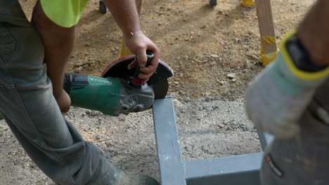 Construction-workers-cutting-steel-tubing-using-electric-disc-saw-making-a-frame