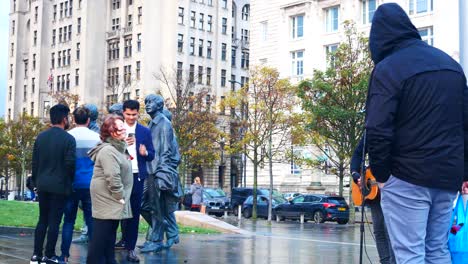 Singer-busker-performing-alongside-Beetles-band-group-statue-on-Liverpool-city-waterfront