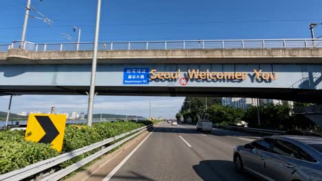 El-Punto-De-Vista-Del-Conductor-Conduciendo-En-La-Autopista-Olympic-daero-Pasando-Por-Seúl-Le-Da-La-Bienvenida-A-Firmar-En-El-Puente-Magok