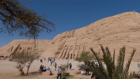 Turistas-Frente-A-La-Entrada-Del-Templo,-Estatuas-De-Ramses-Ii,-Templo-Tallado-En-La-Ladera-De-La-Montaña-En-Abu-Simbel