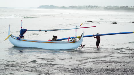 Fisherman-preparing-small-traditional-fishing-boat-on-beach-shore-in-Southeast-Asia
