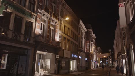 Tilt-down-of-shopping-district-in-Ghent,-Belgium-at-night