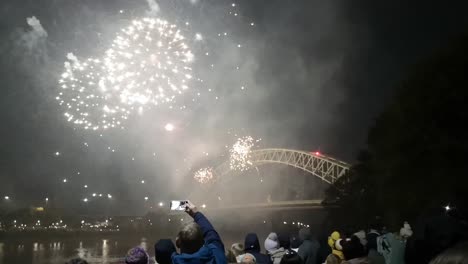 Crowd-watch-colourful-fireworks-glittering-on-Silver-Jubilee-bridge,-Widnes