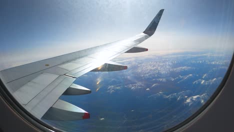 Jet-Plane-Wing-And-Wing-Flaps-Seen-Through-Glass-Window-On-A-Sunny-Weather