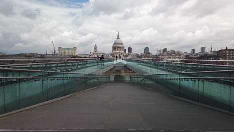 Commuters-and-pedestrians-walking-across-Millennium-Bridge,-London-with-St-Paul's-Cathedral-in-the-background,-early-in-the-morning