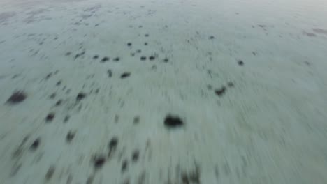 Komodo-Island-Indonesia---Schneller-Flug-In-Geringer-Höhe-über-Seichtes-Ozeanwasser-Und-Aufwärts-Zu-Silhouettierten-Inseln-Am-Horizont