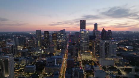 Vista-Aérea-Alrededor-Del-Horizonte-Iluminado-De-Houston,-Atardecer-Colorido-En-Texas,-Estados-Unidos---Dando-Vueltas,-Disparo-De-Drones