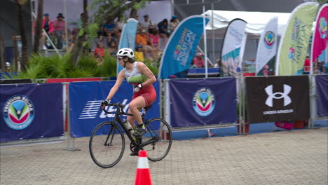 Slow-motion-of-a-female-athlete-starting-the-cycling-stage-at-a-triathlon-riding-her-bike-wearing-a-helmet