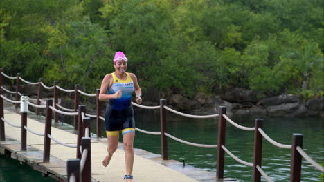 Slow-motion-of-a-female-athlete-running-crossing-a-bridge-in-a-triathlon-competition-after-finishing-the-swimming-stage