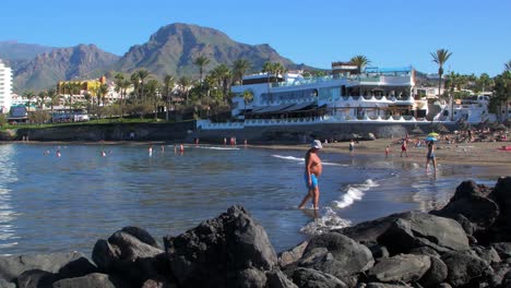 Menschen,-Die-Warmes-Wetter-Und-Einen-Ruhigen-Atlantik-An-Einem-Sonnigen-Sommertag-Am-Strand-Von-Playa-De-Las-Americas-Genießen,-Breite-Handaufnahme