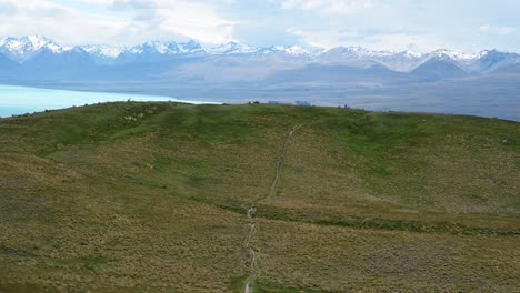 Dos-Personas-Caminando-Por-Una-Estrecha-Ruta-De-Senderismo-Con-Una-Impresionante-Cordillera-De-Fondo