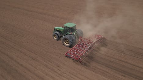 Spring-tooth-harrow-behind-farm-tractor-loosens-top-soil-for-planting