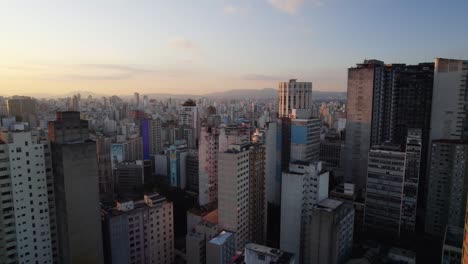Flying-in-middle-of-old-high-rise-in-Sao-Paulo-city,-sunset-in-Brazil---Aerial-view