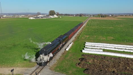 Vista-De-Drones-De-Un-Tren-De-Pasajeros-De-Vapor-Que-Sopla-Mucho-Humo-Y-Vapor-Parado-En-Un-Día-Soleado-De-Otoño