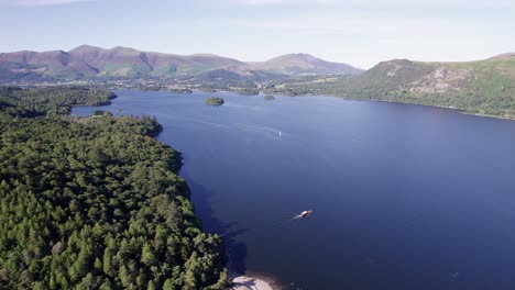 High-drone-shot-flying-left-over-Derwent-Water-with-boats-on-the-lake-on-a-sunny-day,-Lake-District,-Cumbria,-UK