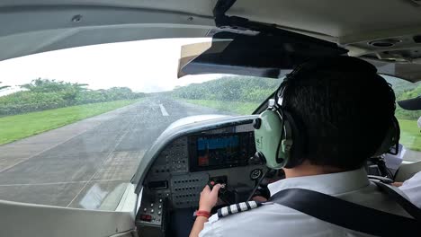 Single-engine-airplane-take-off-with-pilot-and-copilot-banking-into-ocean,-Aerial-cockpit-handheld-view