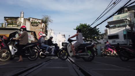 Motorrad--Und-Fußgängerverkehr-über-Bahngleise-Auf-Einem-Bahnübergang-In-Saigon-An-Einem-Sonnigen-Klaren-Morgen-Aus-Einem-Niedrigen-Winkel